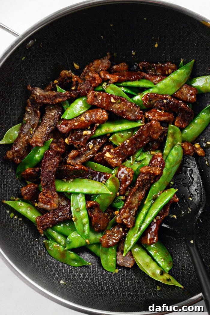 The Crispy Honey Sriracha Beef and Snow Peas being tossed in the skillet as the sauce beautifully thickens.