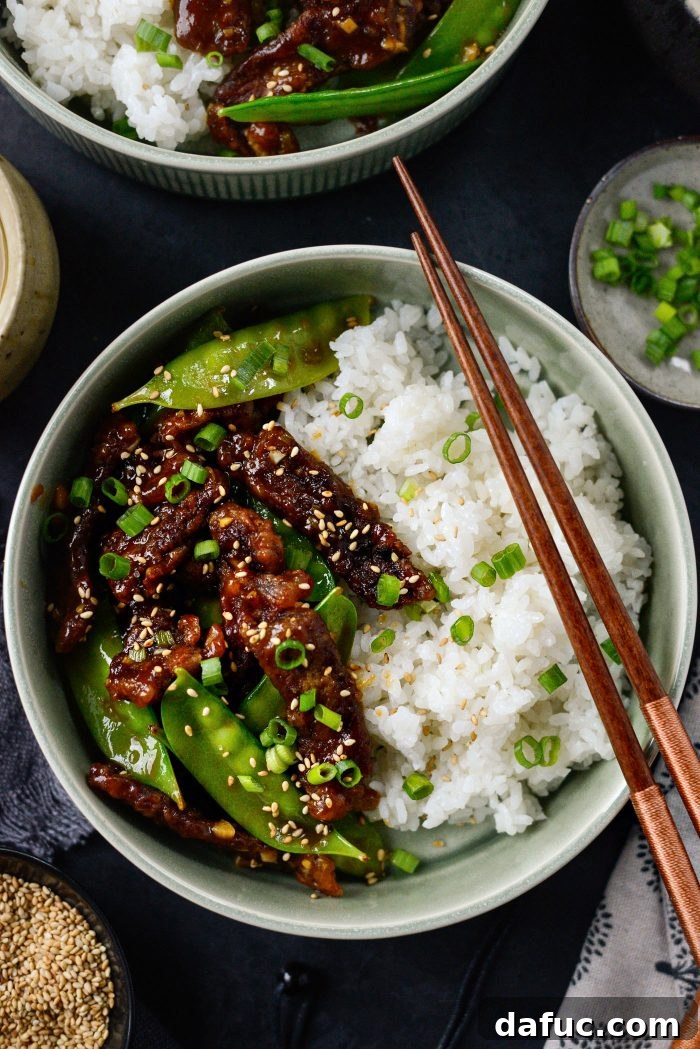 Spicy-Sweet Crispy Beef and Snap Peas 21 A perfectly plated dish of Crispy Honey Sriracha Beef and Snow Peas over white rice, garnished with green onions and sesame seeds.