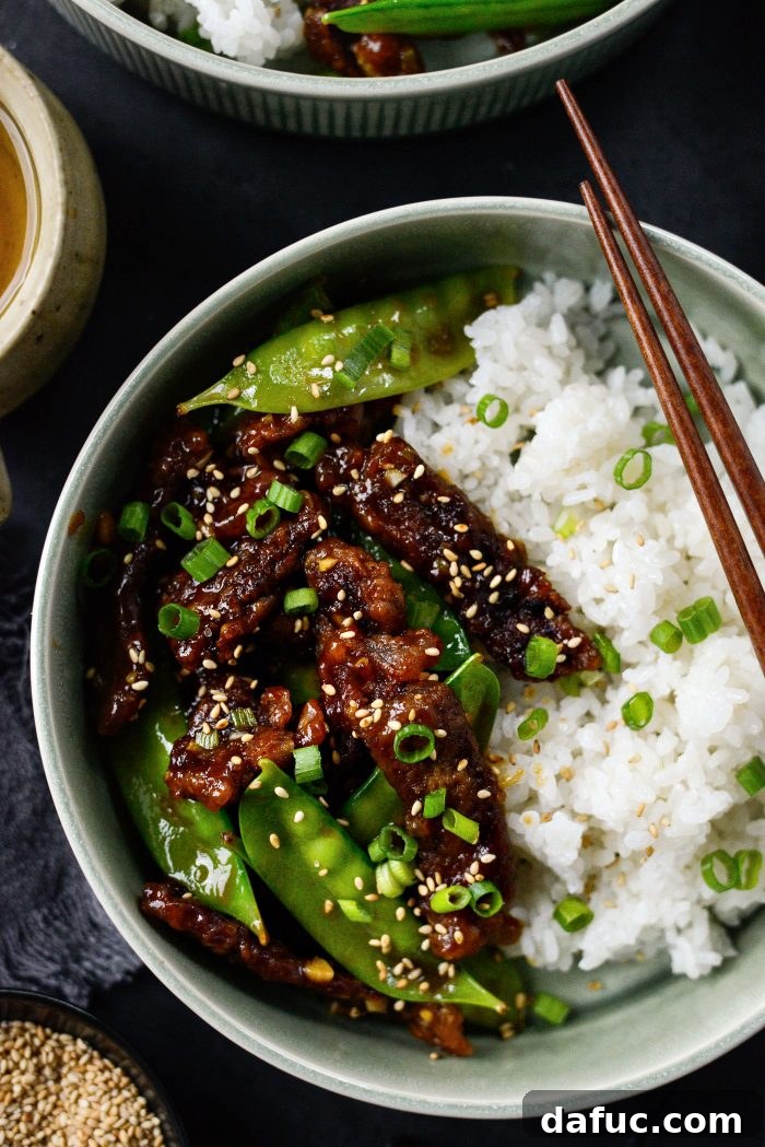 Spicy-Sweet Crispy Beef and Snap Peas 22 A close-up view of the finished Crispy Honey Sriracha Beef and Snow Peas dish, highlighting the texture of the beef and the vibrant green snow peas.
