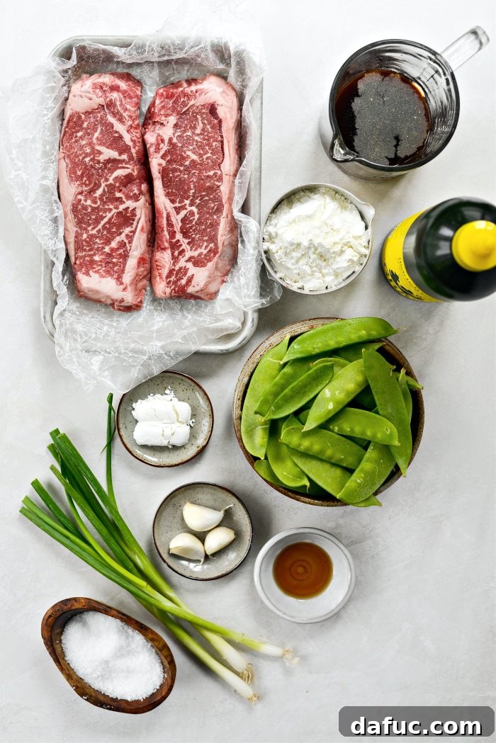 Spicy-Sweet Crispy Beef and Snap Peas 4 A vibrant collection of fresh ingredients laid out on a cutting board, including steak, honey, sriracha, snow peas, garlic, and green onions.