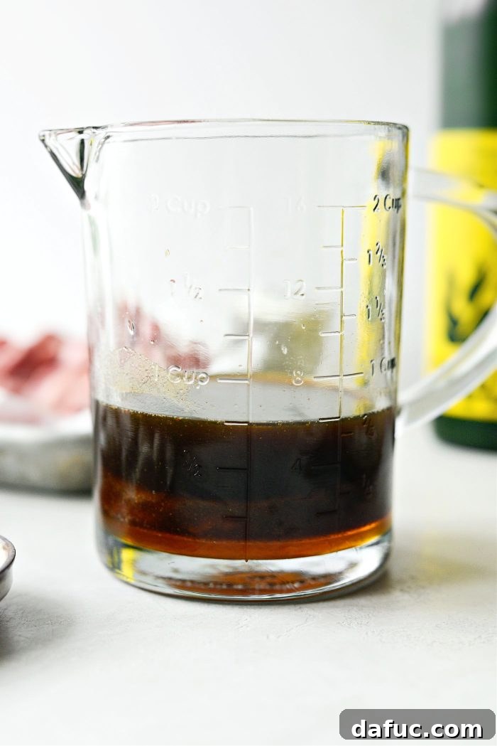 Spicy-Sweet Crispy Beef and Snap Peas 5 Ingredients for the honey sriracha stir-fry sauce being whisked together in a liquid measuring cup.