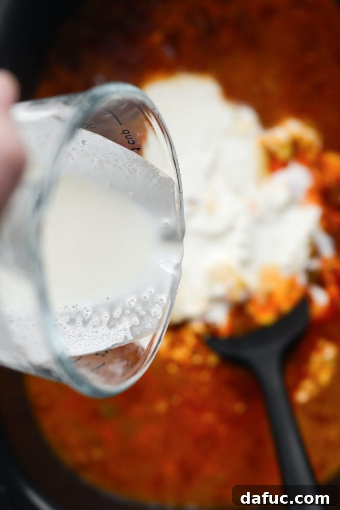 Pouring heavy cream into the slow cooker chili