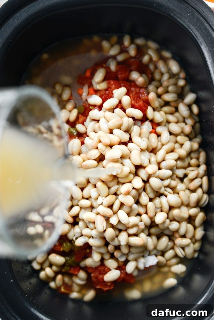 Adding beans and broth to the slow cooker chili