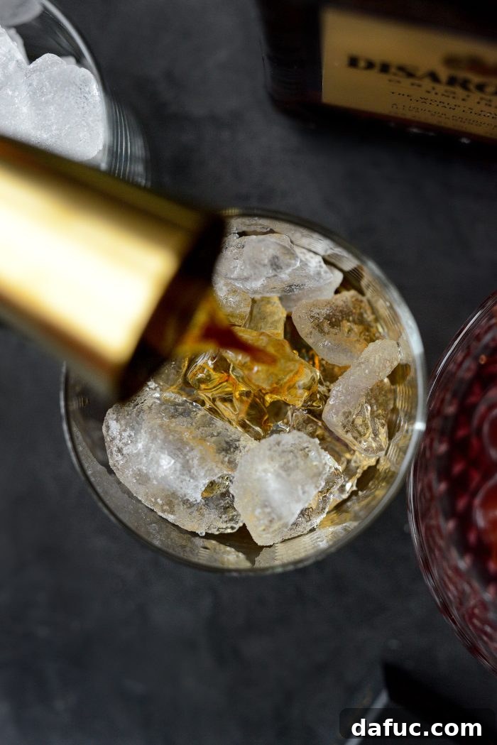 Spiced Amaretto Elixir 6 Pouring amaretto into a glass with ice