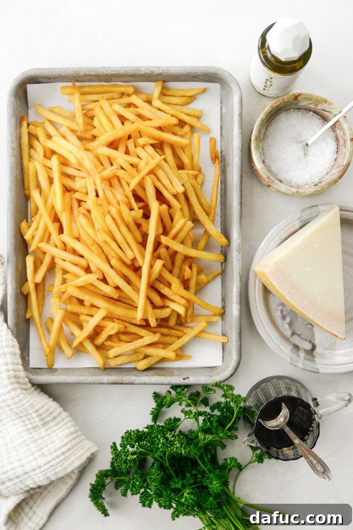 Decadent Truffle Parmesan Fries 4 A selection of fresh ingredients laid out: French fries, white truffle oil, flaky salt, parmesan cheese, balsamic glaze, and fresh parsley