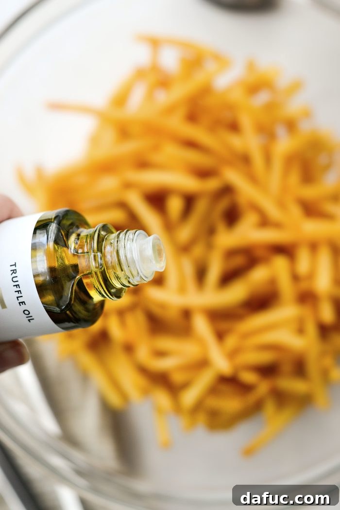 Decadent Truffle Parmesan Fries 6 Drizzling white truffle oil over crispy French fries in a mixing bowl