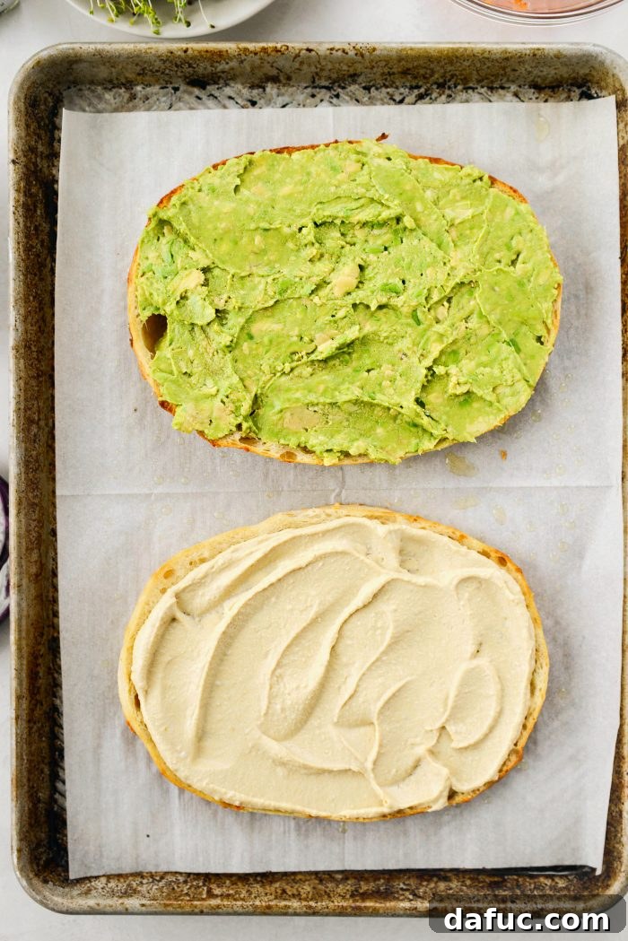 Vibrant Rainbow Stack 9 Spreading hummus on the bottom focaccia half and smashed avocado on the top half