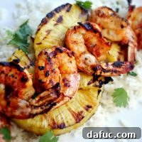 Spicy Chipotle Shrimp Skewers on a plate with pineapple and rice