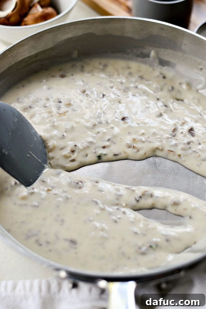 The homemade cream of mushroom soup simmering and thickening in the skillet.