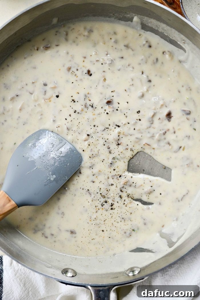Seasoning the homemade cream of mushroom soup with kosher salt and freshly ground black pepper.