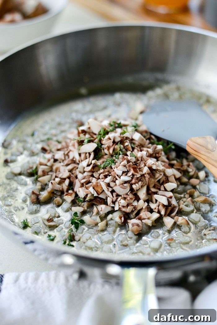 Adding minced cremini mushrooms and fresh thyme leaves to the sautéed shallots.