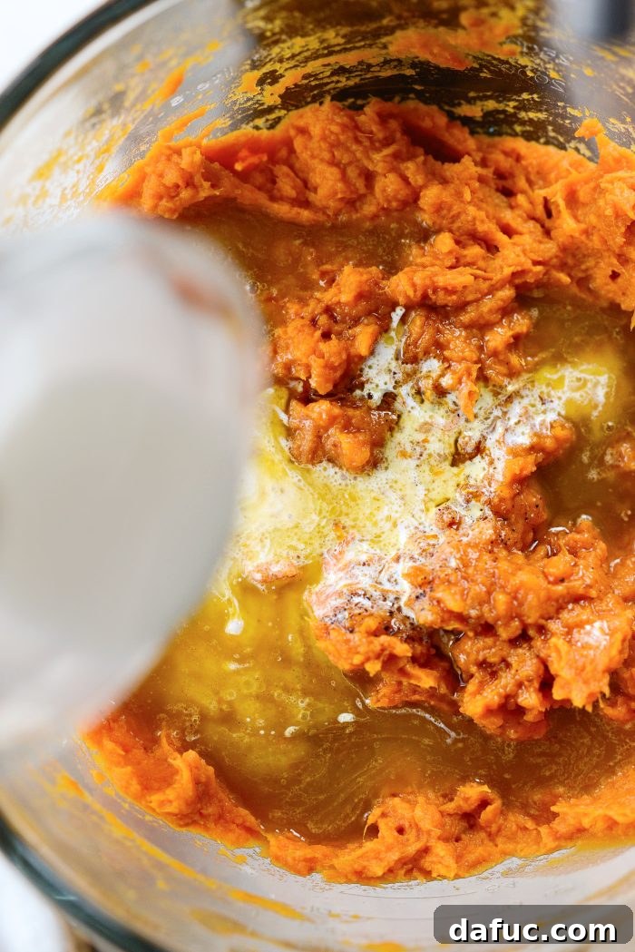 Pouring half and half into sweet potato mixture in a mixer