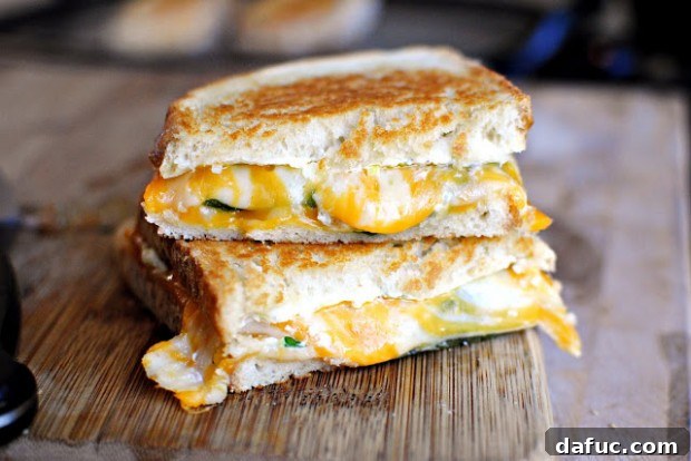 Blazing Popper Grilled Cheese 2 Irresistible Jalapeño Popper Grilled Cheese sandwich with melted cheese and fresh peppers, served on a cutting board