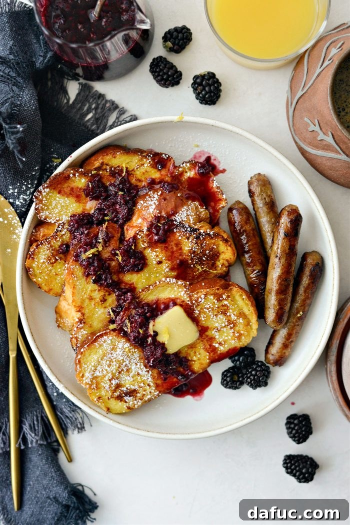 Sourdough French Toast with Berry Compote 2 Buttermilk French Toast, golden brown slices on a plate with sauce and lemon zest