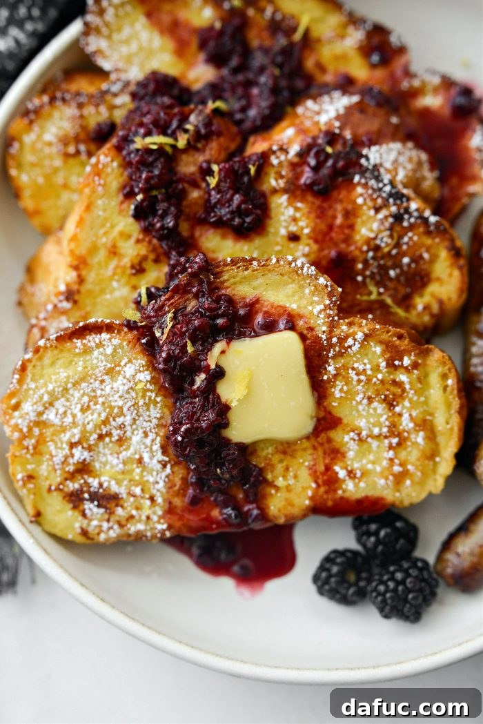 Sourdough French Toast with Berry Compote 23 A stack of Buttermilk French Toast on a plate with butter and syrup