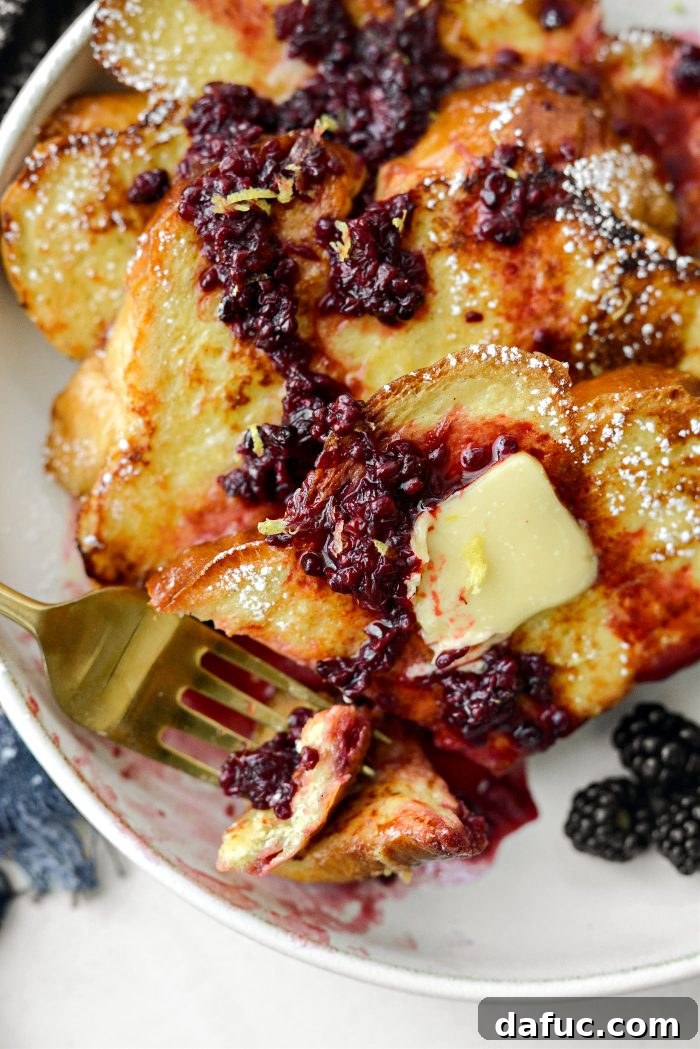 Sourdough French Toast with Berry Compote 24 A close-up shot of Buttermilk French Toast with a fork, emphasizing texture