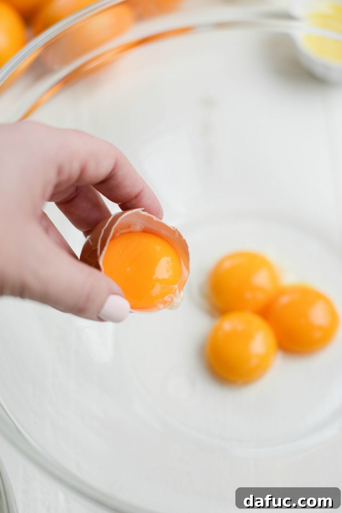 Adding egg yolks to a bowl