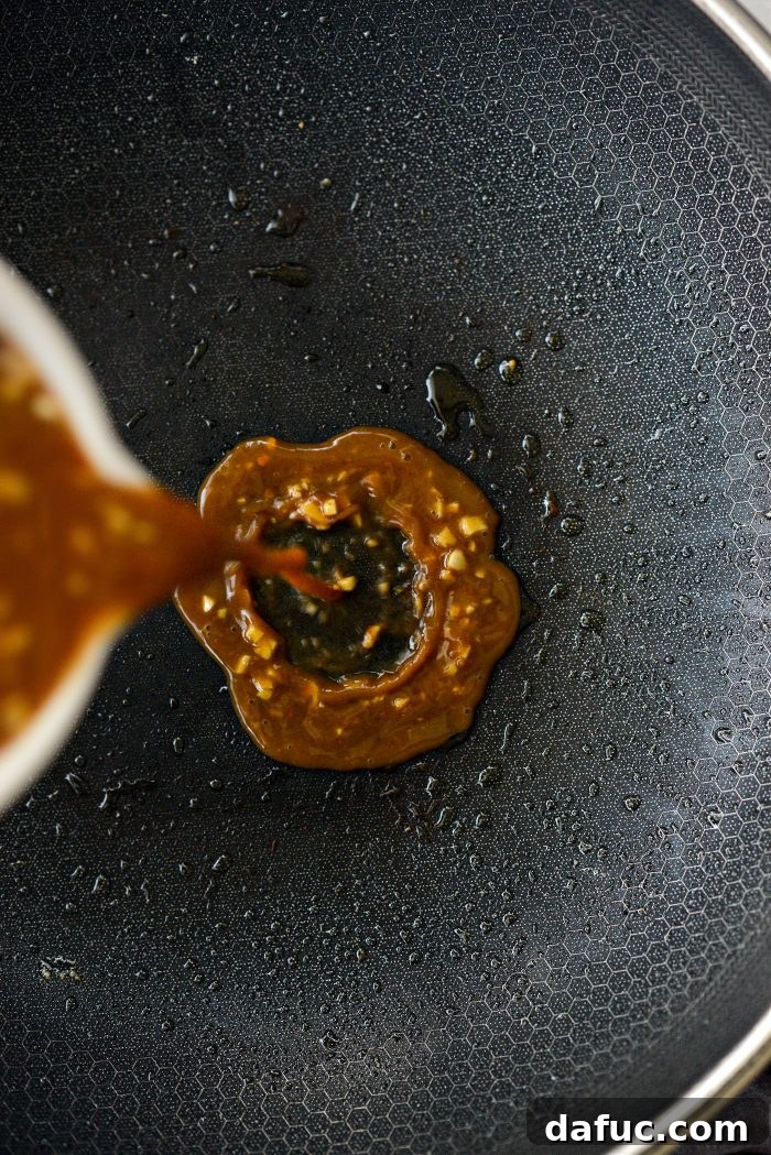 Sticky Sweet Bourbon Chicken 13 Pouring Bourbon Chicken sauce into an empty wok