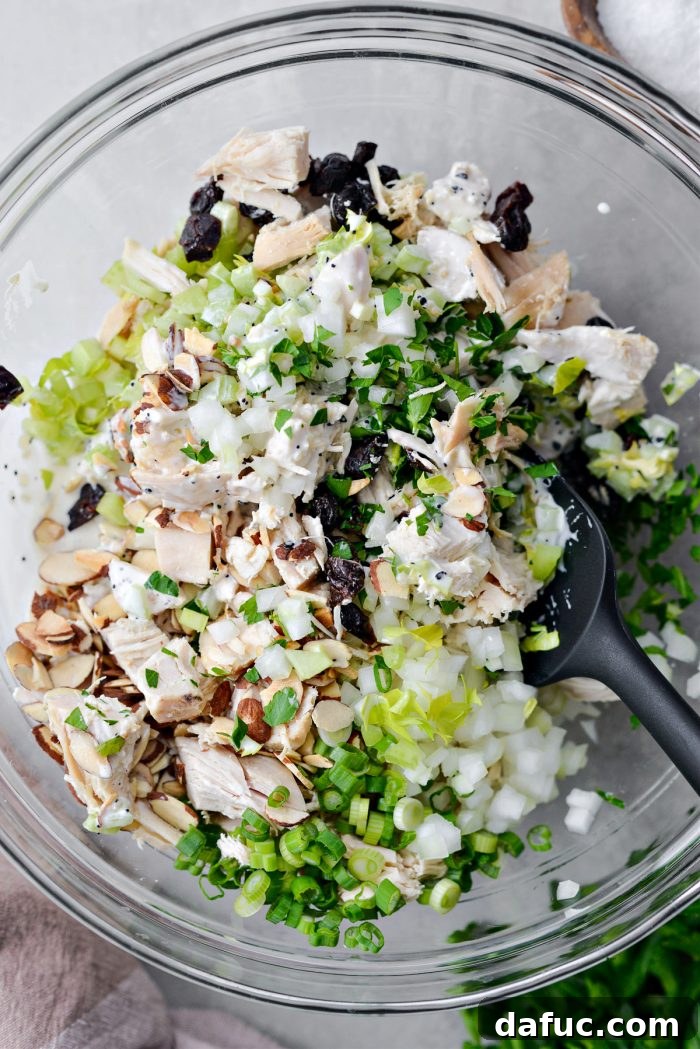 Tossing the Cherry Toasted Almond Chicken Salad until all ingredients are evenly coated with dressing.