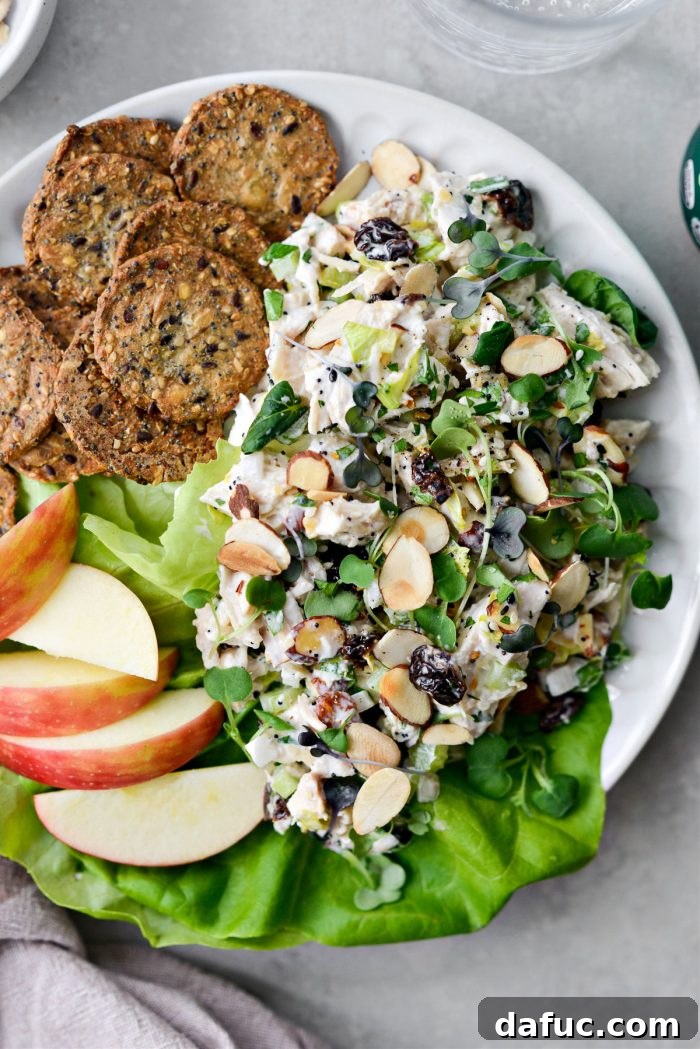 A serving of Cherry Toasted Almond Chicken Salad, garnished with fresh greens and a sprinkle of seasoning.
