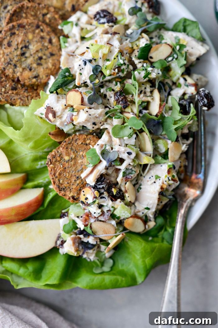 A beautifully presented bowl of Cherry Toasted Almond Chicken Salad, garnished with fresh herbs.