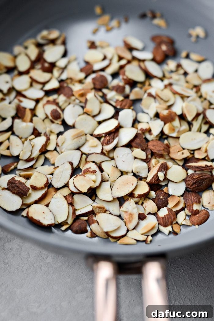 Perfectly toasted sliced almonds, golden brown and fragrant, cooling in a pan.