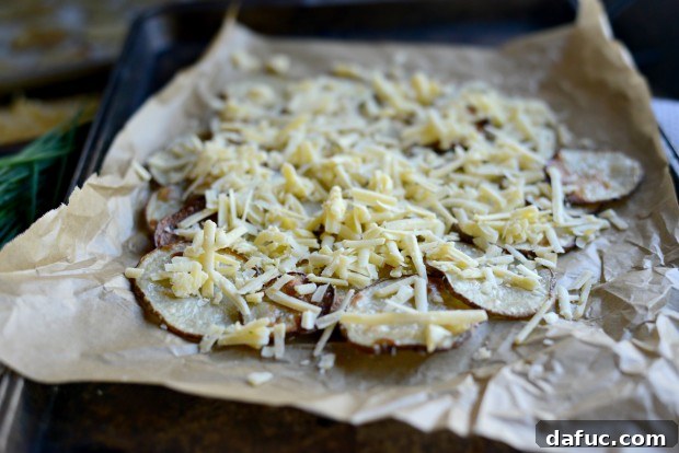 First layer of crispy potato rounds spread on a parchment-lined baking sheet.
