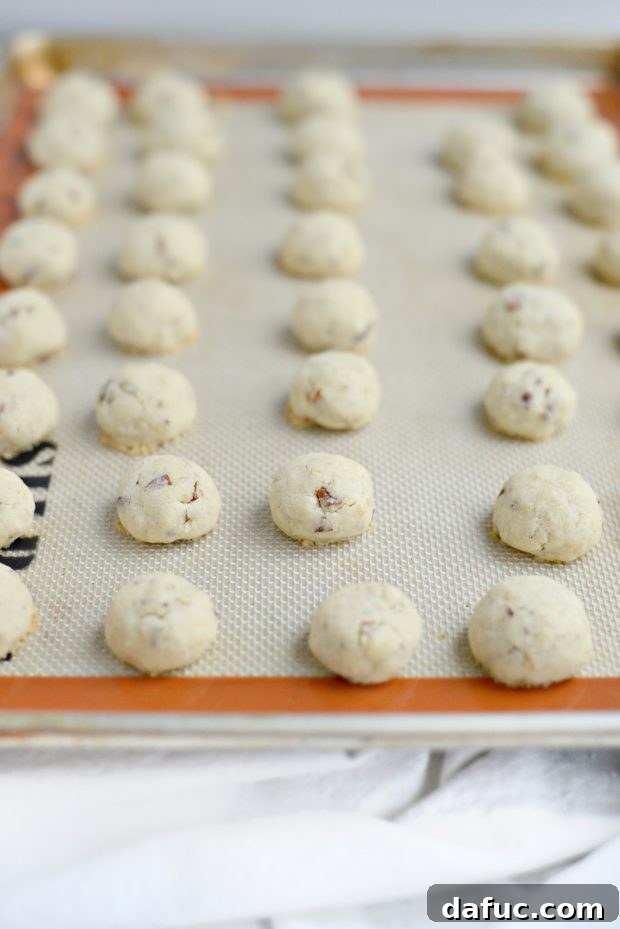 Pecan Dreamscape 7 Unbaked Pecan Dreams Snowball Cookie dough balls arranged on a baking sheet lined with parchment paper.