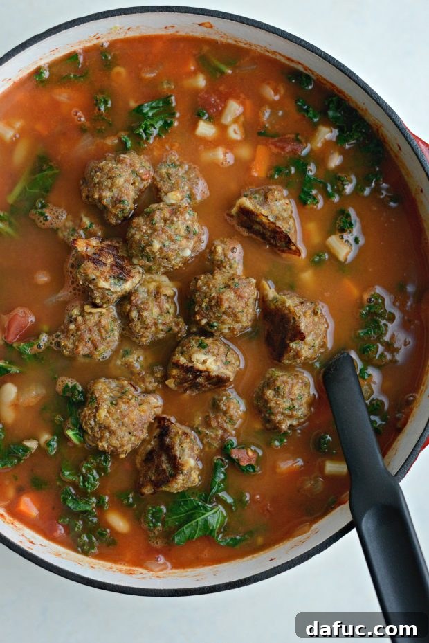 Cooked turkey meatballs being added to the hot minestrone soup.