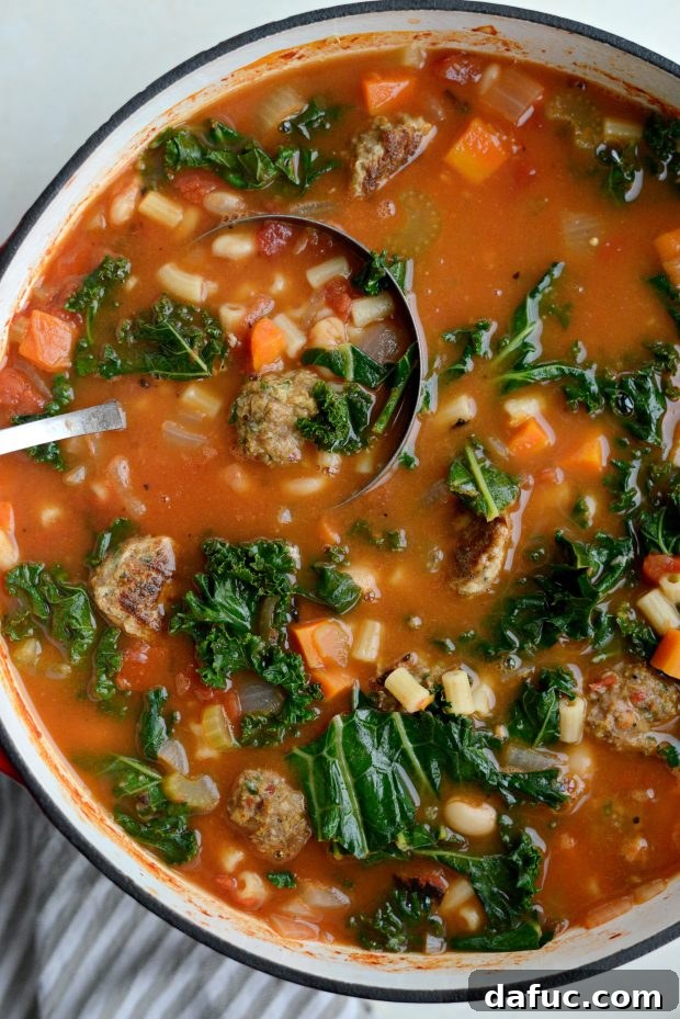 A close-up of a spoon dipping into a bowl of Italian Turkey Meatball Minestrone Soup.