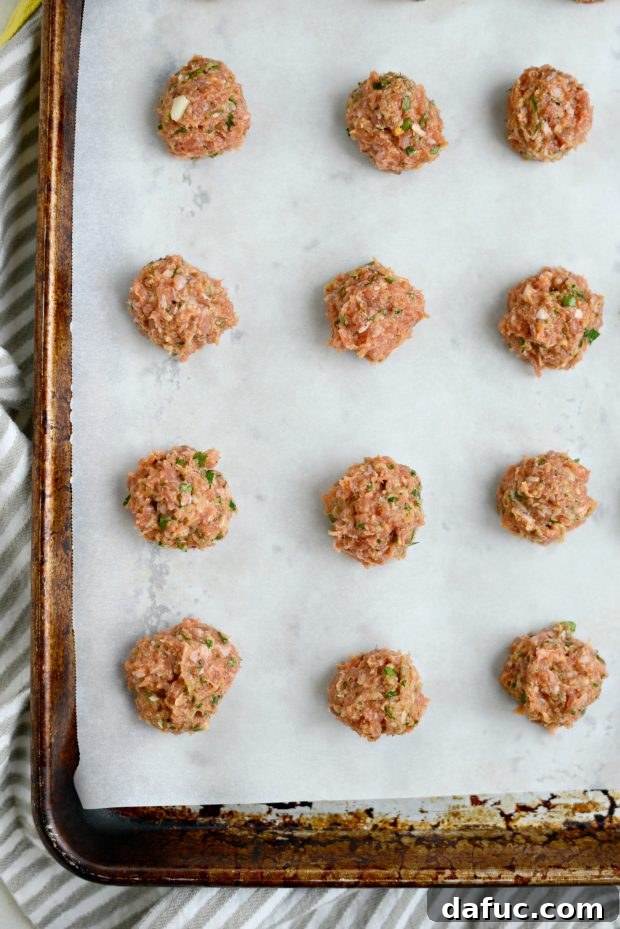 A hand measuring out a tablespoon of meatball mixture to roll into a ball.