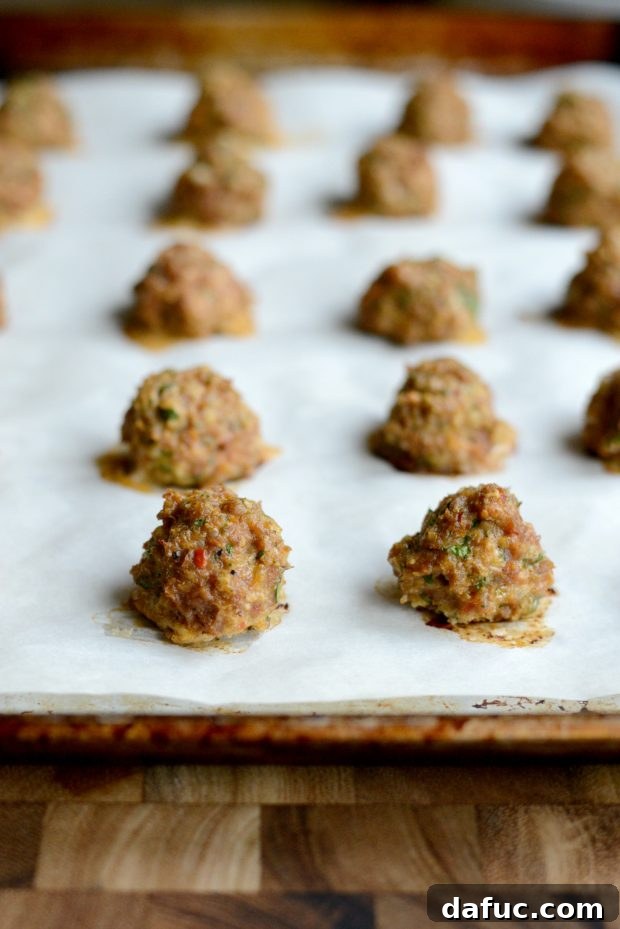 Baked turkey meatballs cooling on a parchment-lined sheet pan.