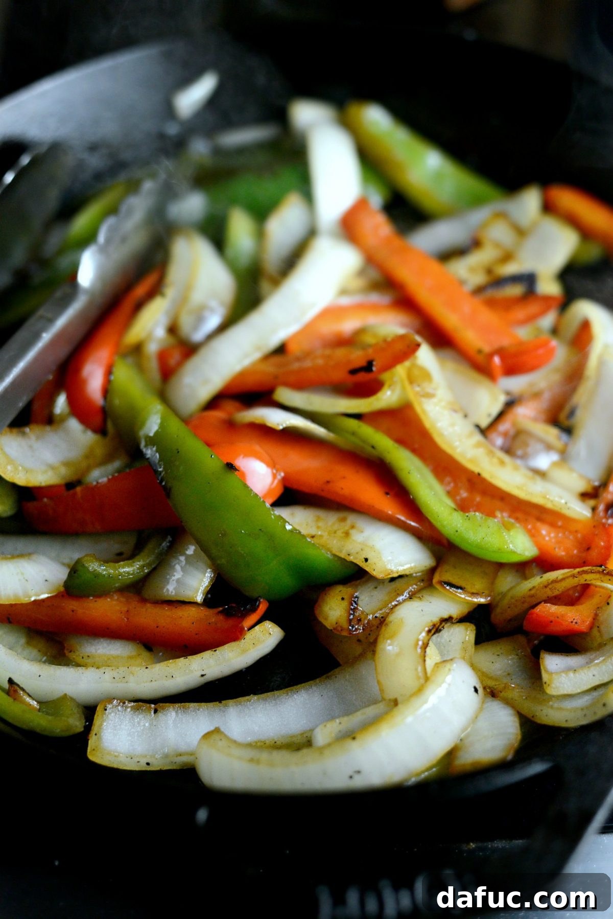 Charring bell peppers and onions in a hot cast iron skillet