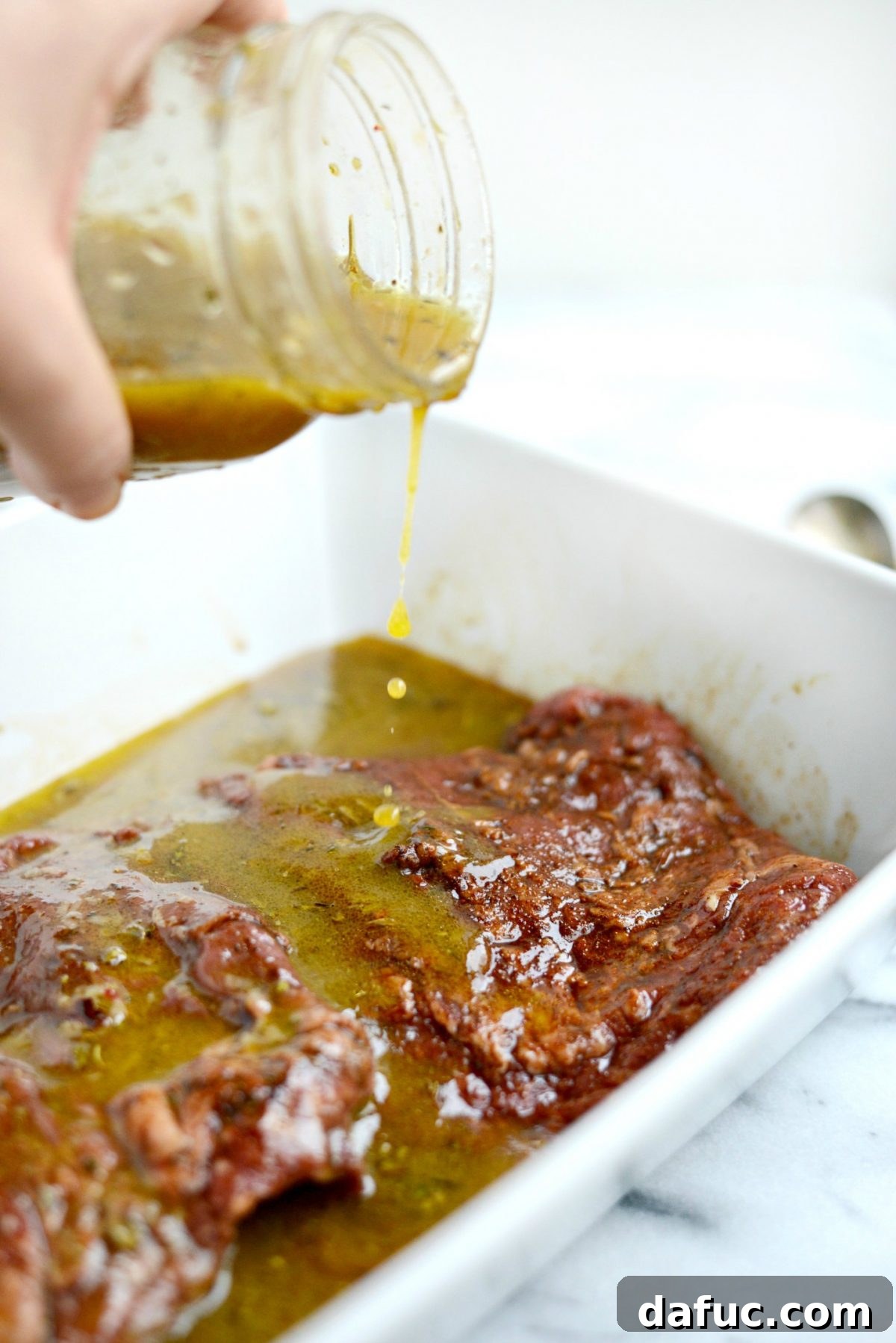 Pouring zesty Italian dressinade over marinated meat