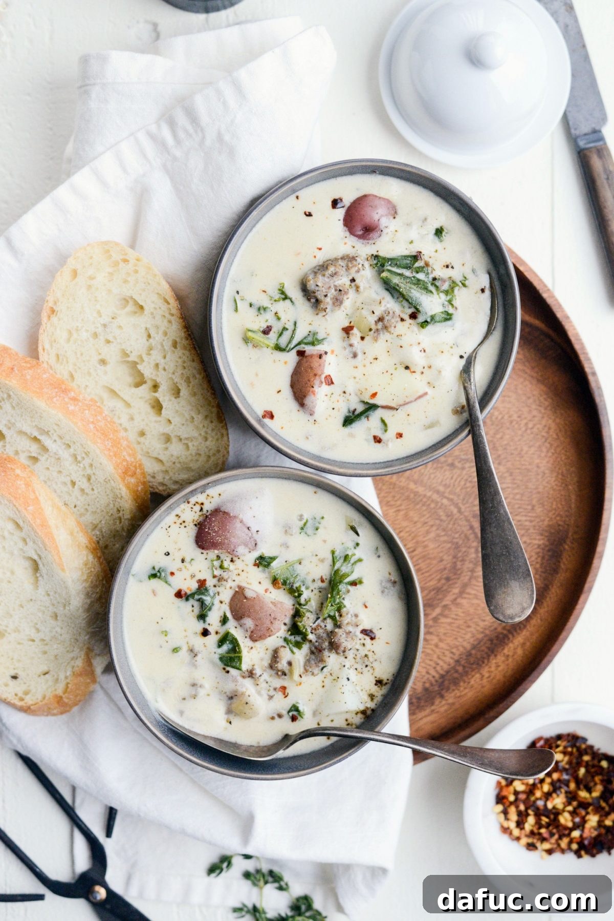 A bowl of Creamy Potato, Sausage and Kale Soup with a spoon, ready to be enjoyed.