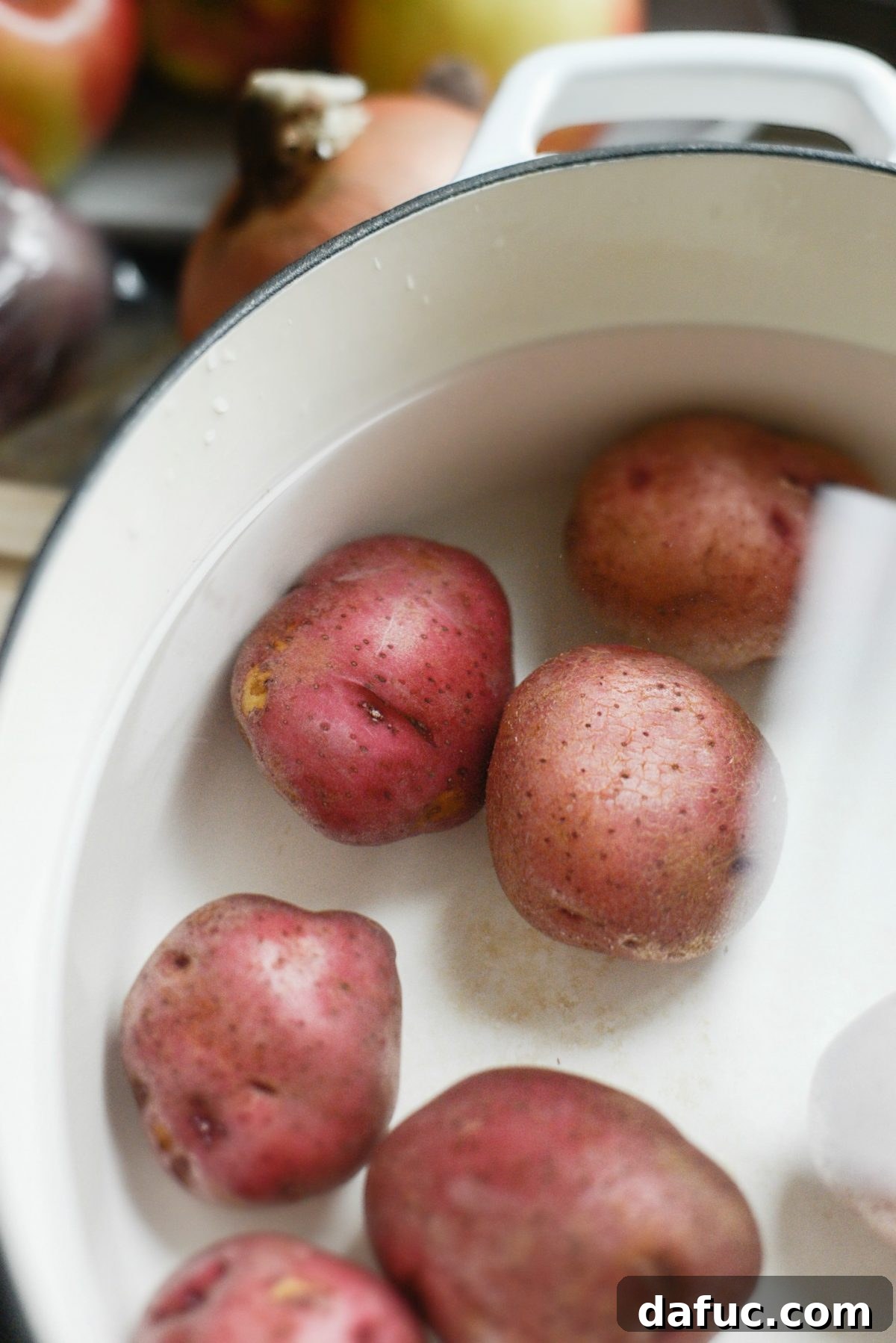 Red potatoes being cooked in a pot, ready for the Creamy Potato, Sausage and Kale Soup recipe.