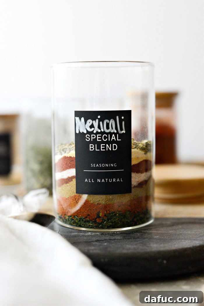 Measuring spices into a glass jar for Mexicali Seasoning