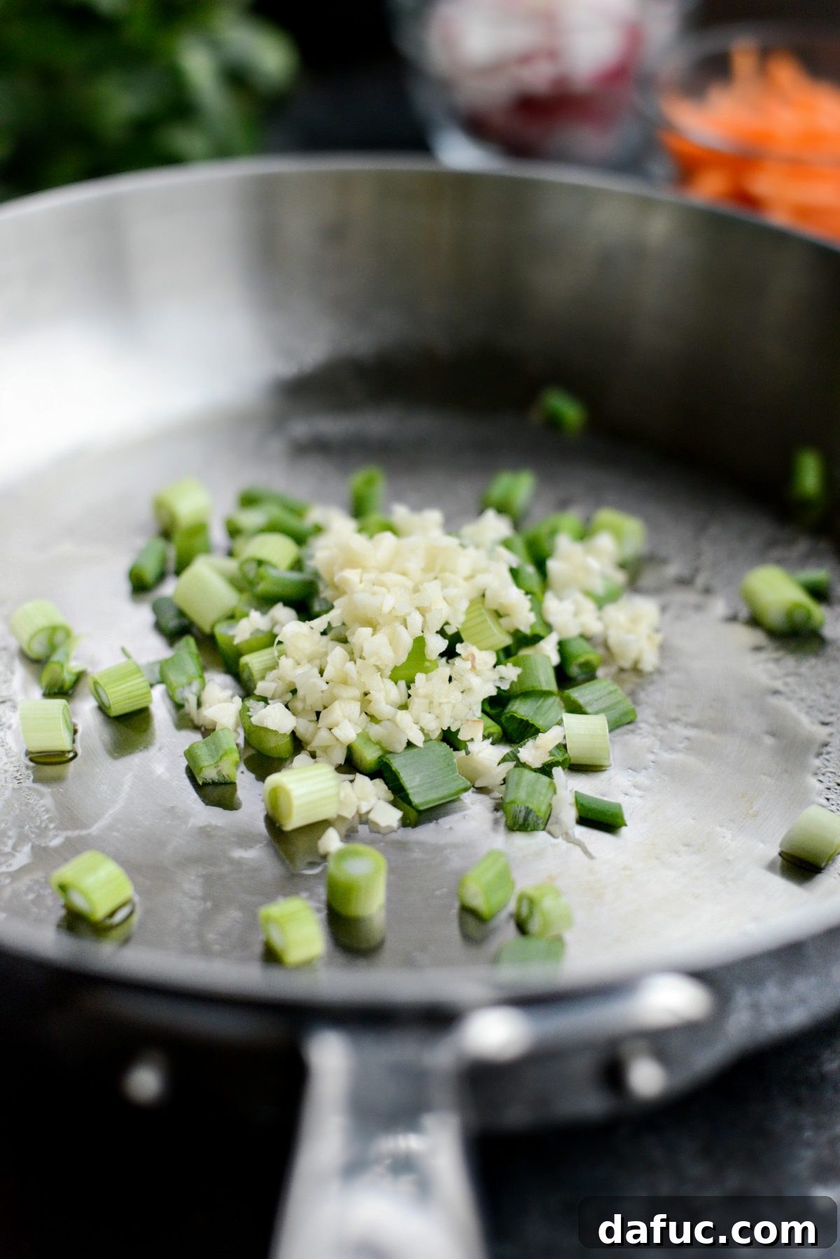 Sautéing green onions and garlic to build the flavor base.