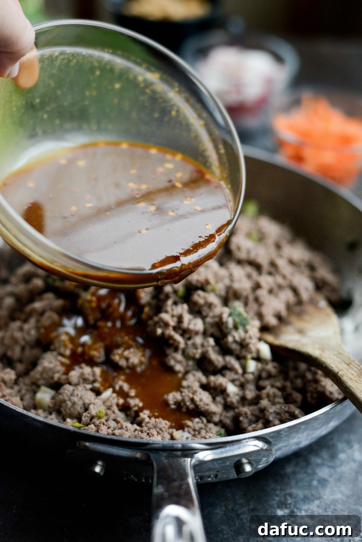 Pouring the ginger hoisin sauce over the browned ground beef.