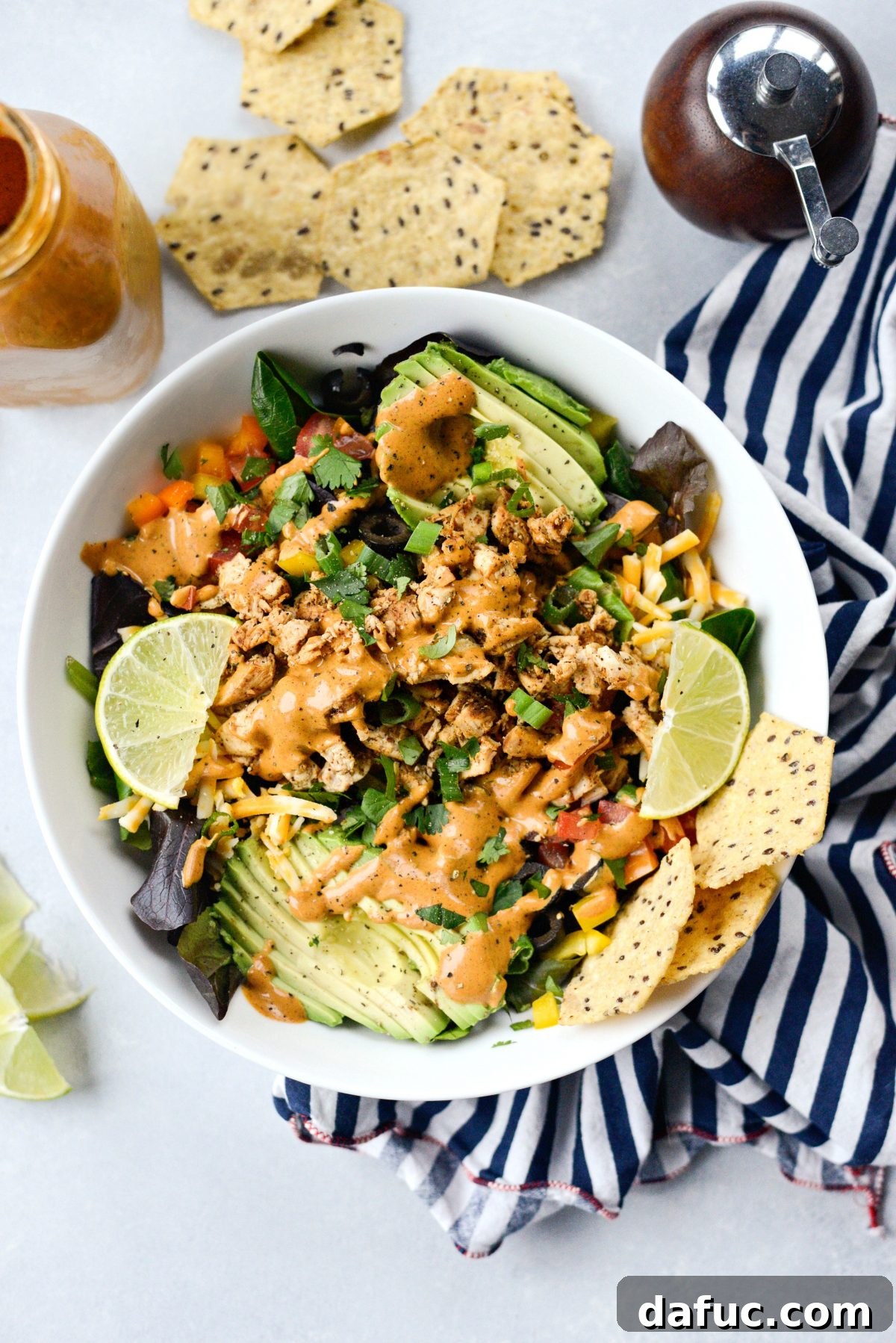 Homemade Southwest Dressing in a jar with a spoon, next to a fresh salad