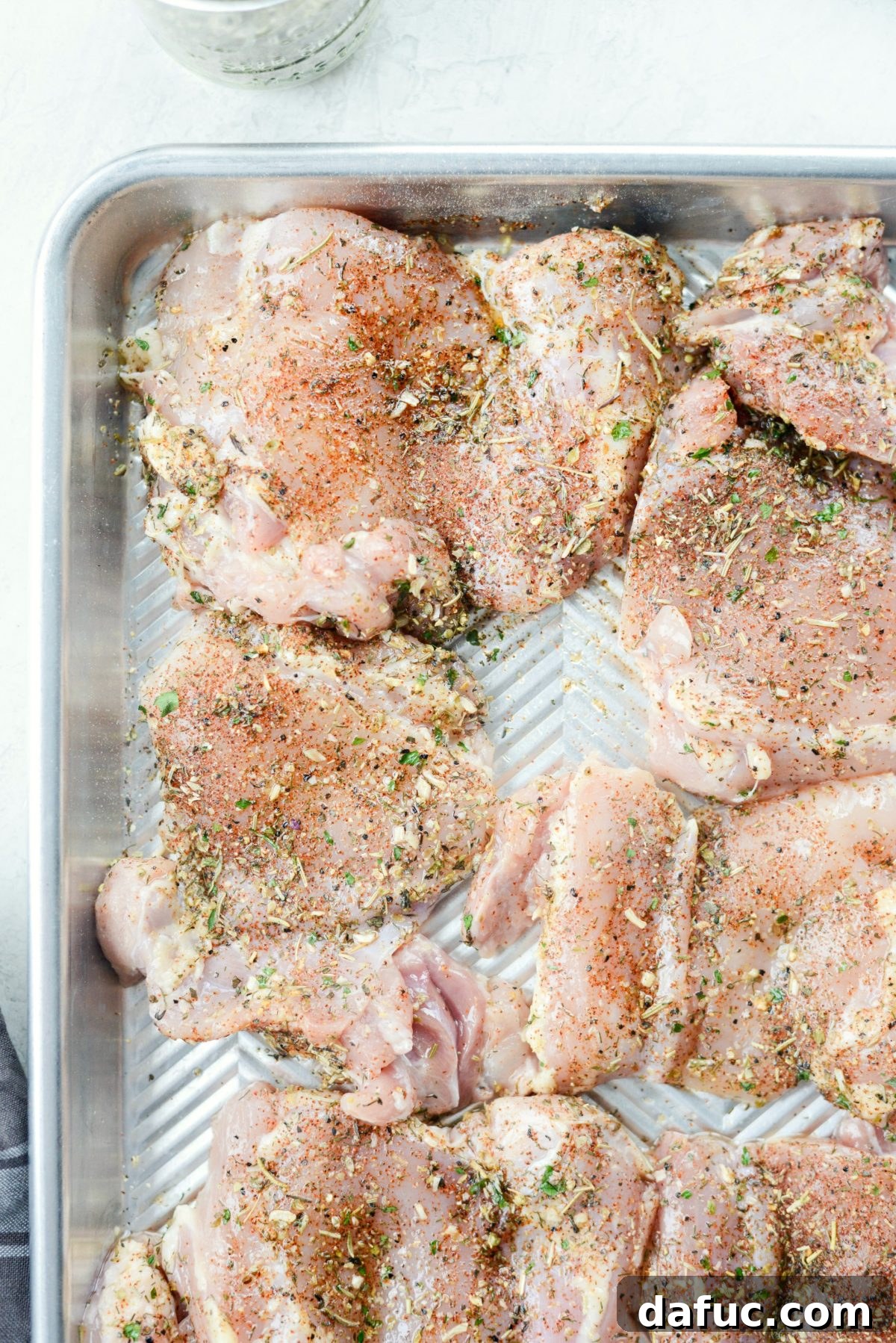 Vibrant Greek Chicken Couscous Bowl 5 Seasoned chicken thighs on a rimmed baking sheet before roasting
