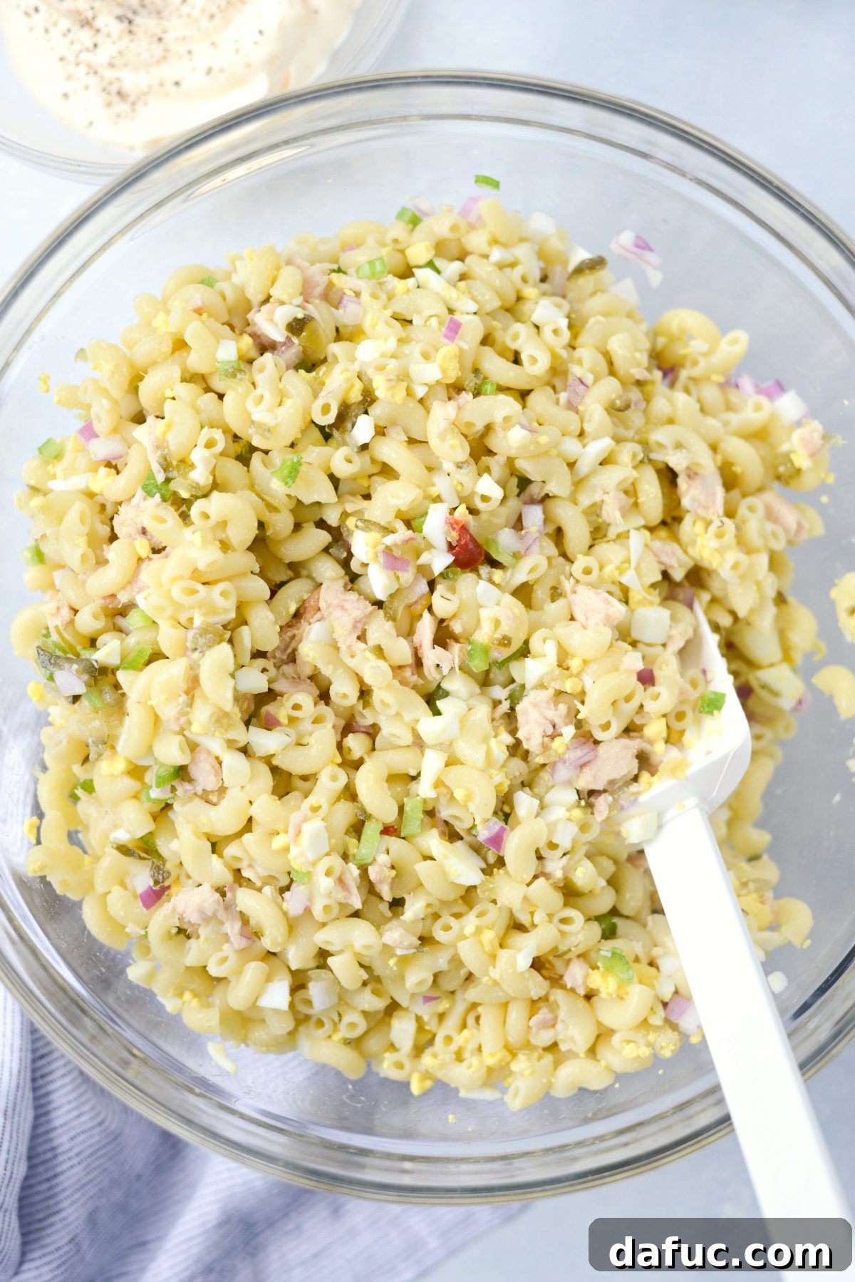 Adding finely diced celery and red onion to the macaroni and tuna mixture