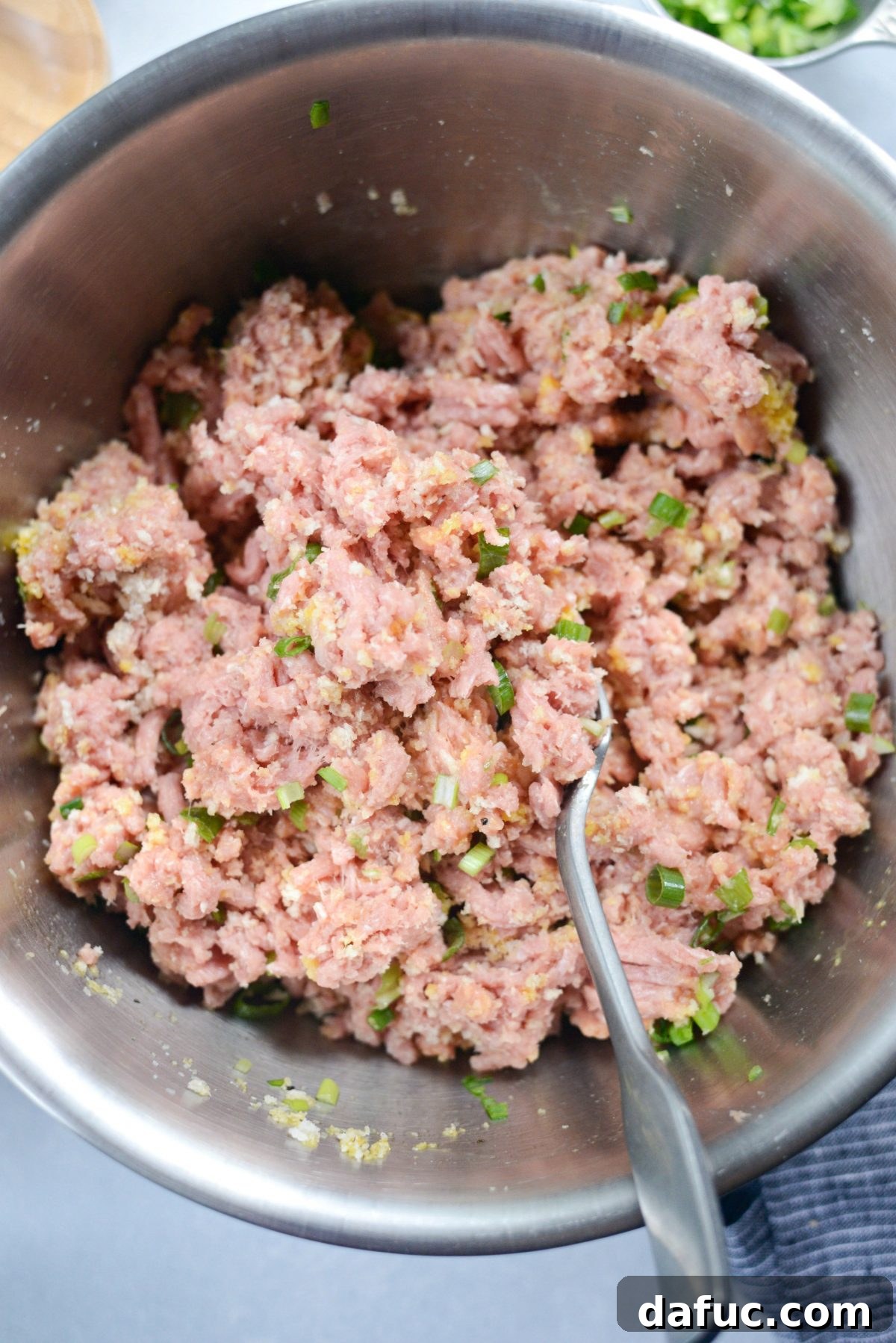Mixing ground turkey with other ingredients for meatballs