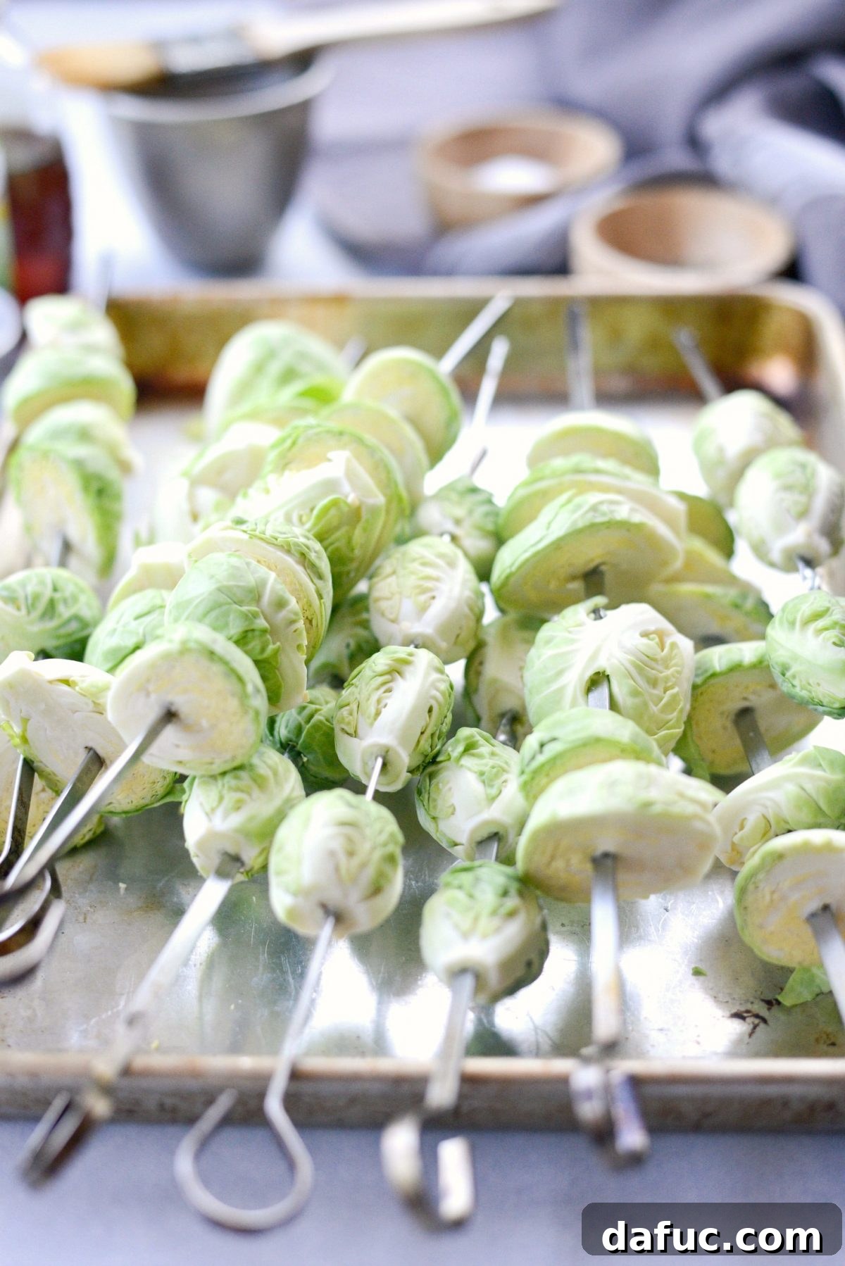 Threading Brussels sprouts onto metal skewers for grilling