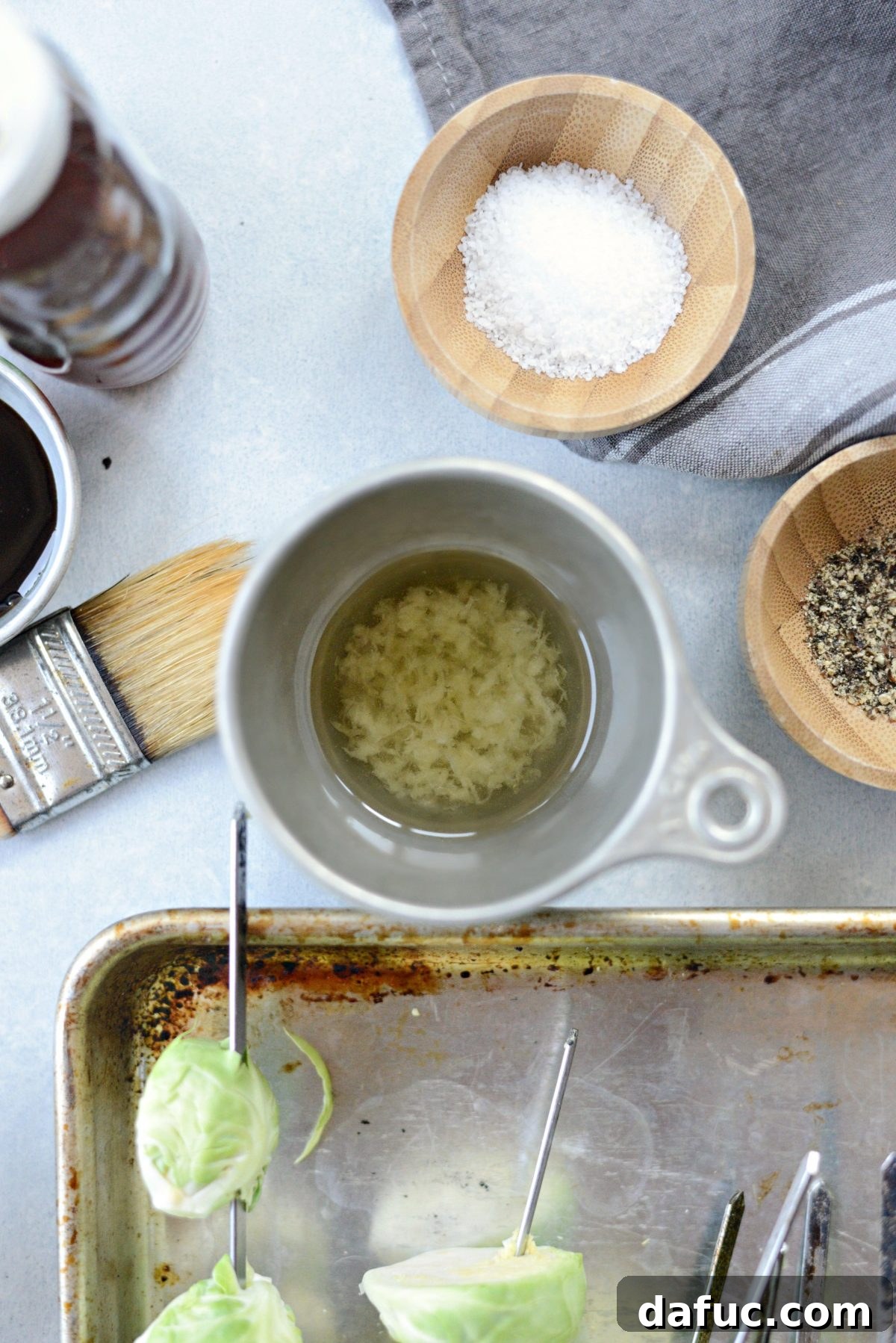 Combining grated garlic with olive oil for brushing Brussels sprouts