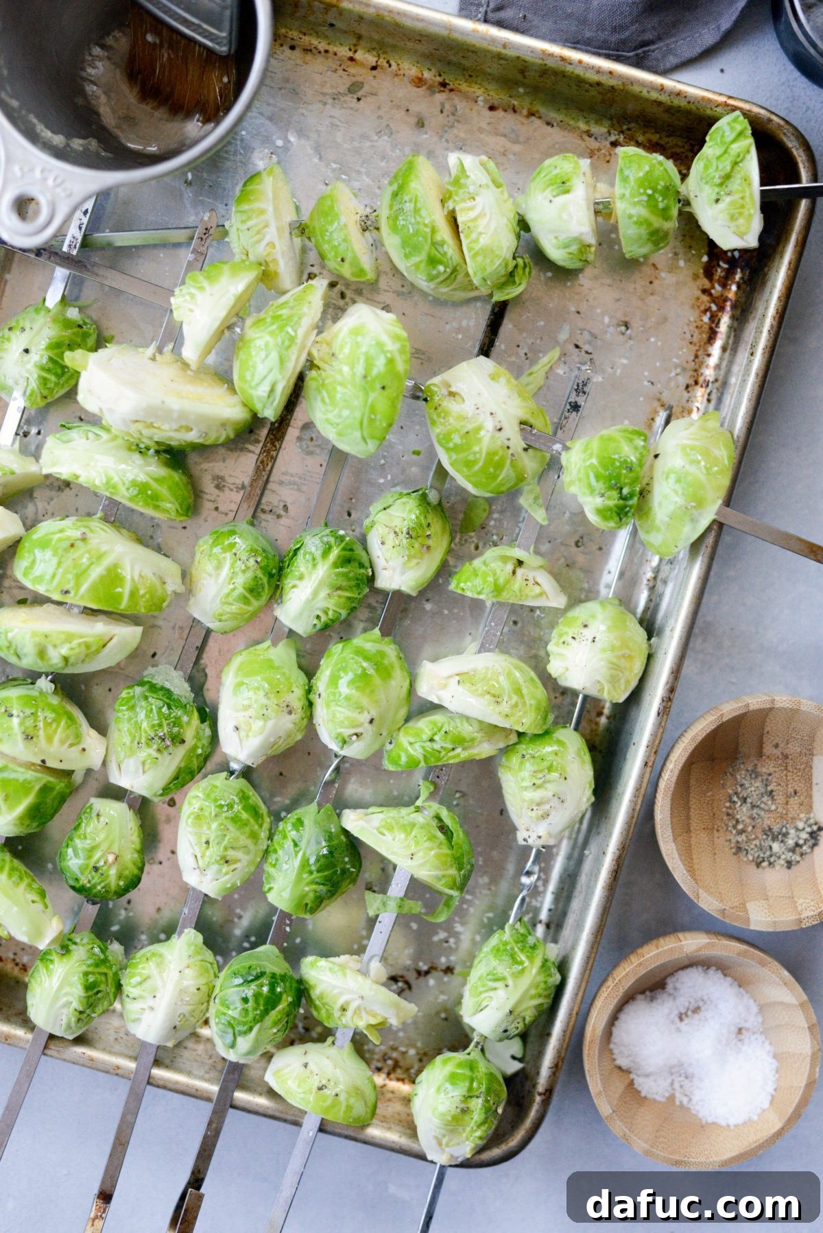 Brushing garlic olive oil onto Brussels sprout skewers before grilling