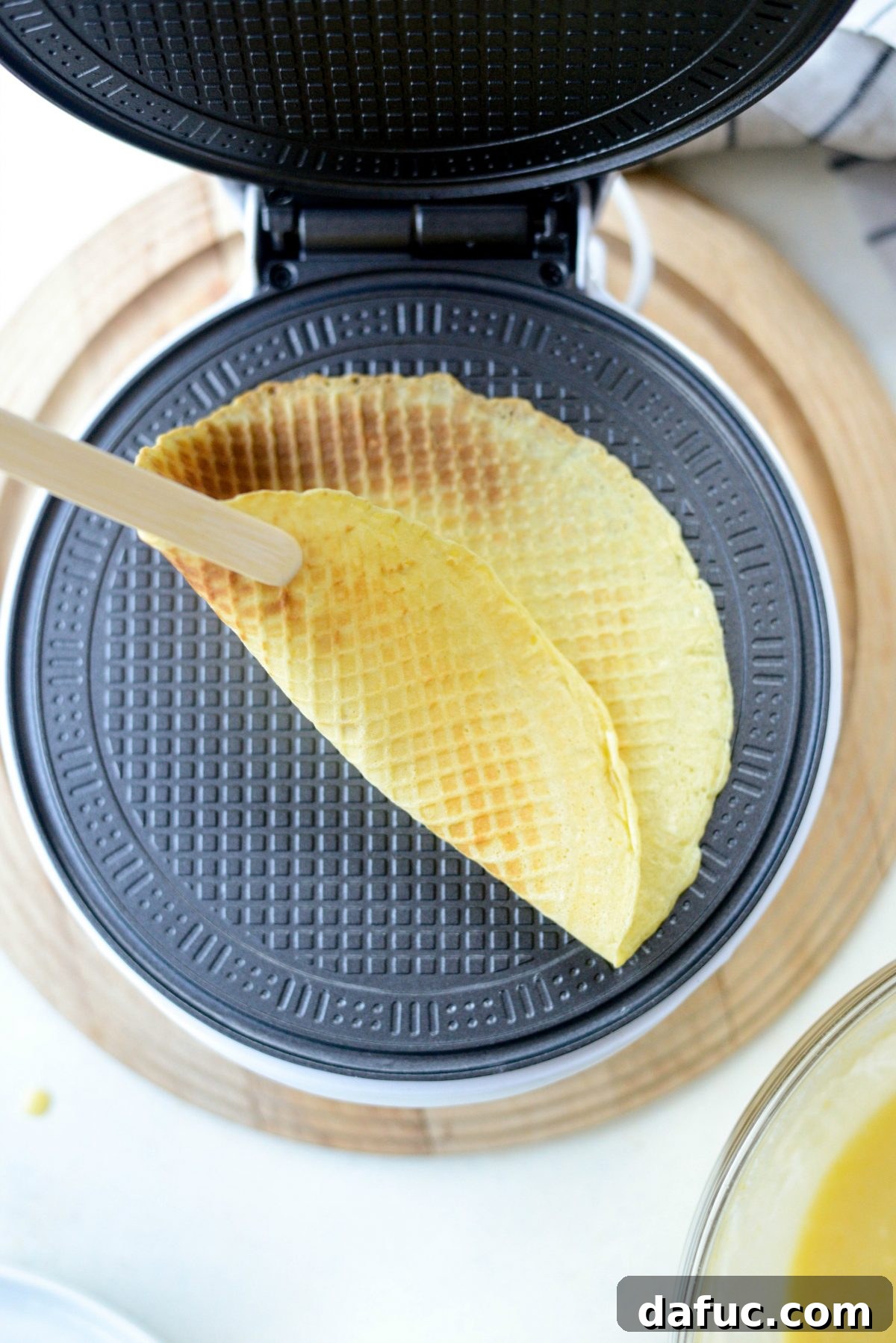 Using wooden tongs to remove a warm waffle