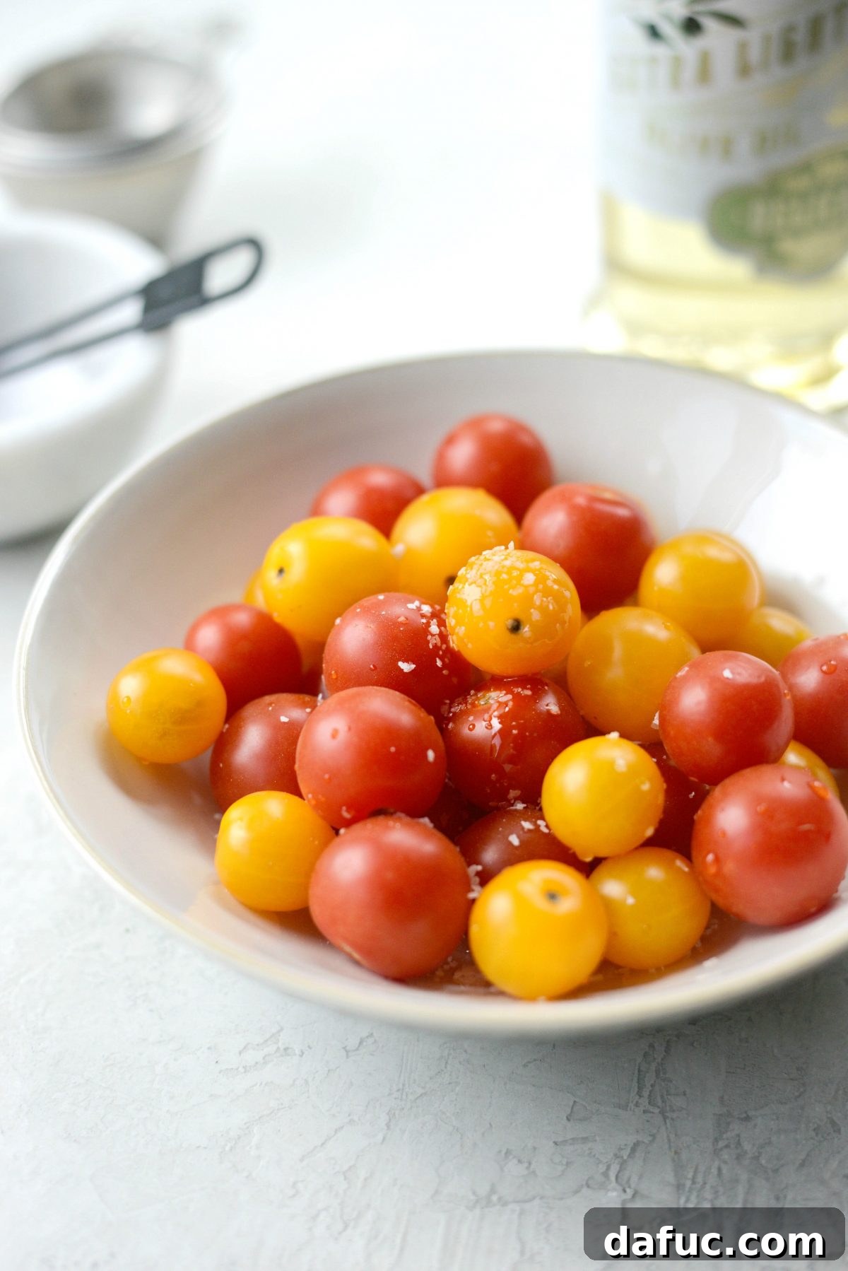 Cherry tomatoes being tossed with olive oil and salt