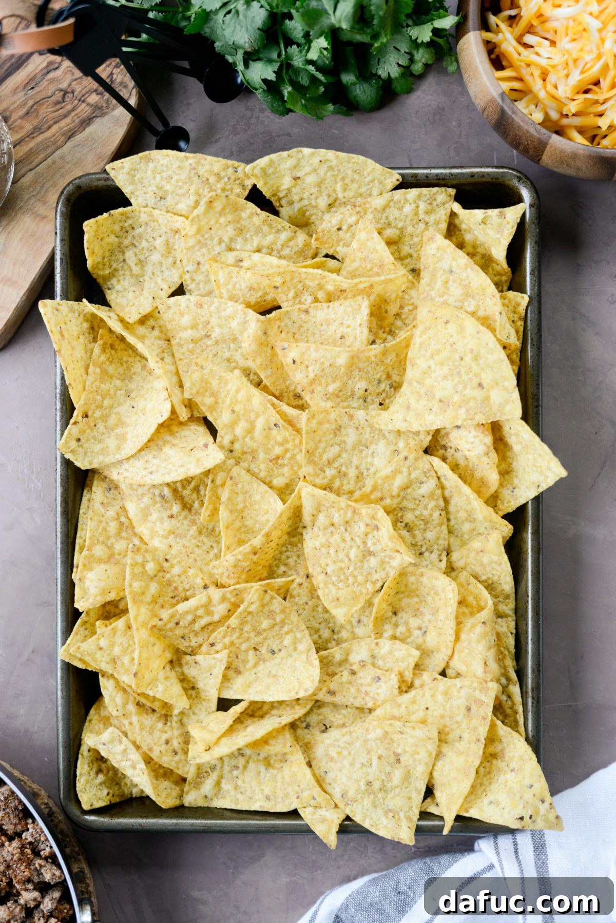 Ultimate Taco Nachos 7 line a small rimmed baking sheet with tortilla chips.