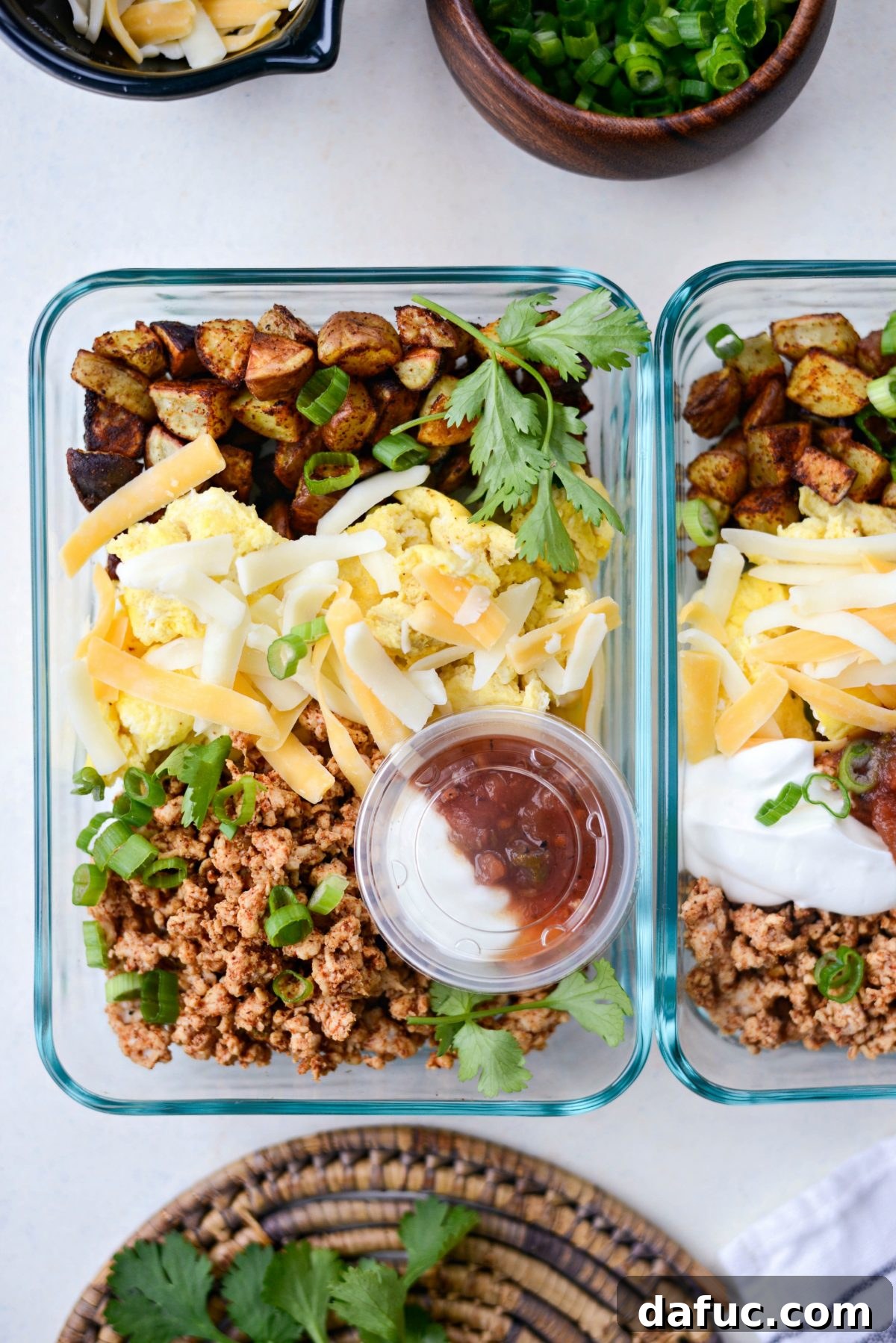 A completed Turkey Taco Breakfast Scramble meal prep container with separate salsa and Greek yogurt cups nestled inside.